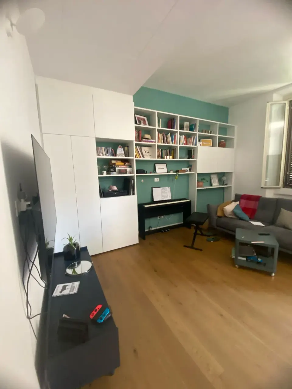 Libreria su misura verde salvia con vano TV e pianoforte